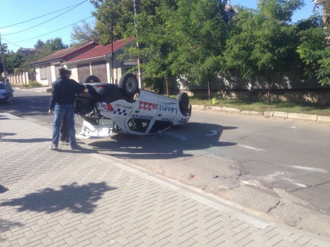 Un taxi, cu roțile în sus după ce s-a ciocnit violent cu un automobil. Accident la intersecția străzilor Suceava cu Paris