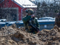 Soldat ucrainean, fotografiat plangand in fata unei gropi comune din Bucha - FOTO