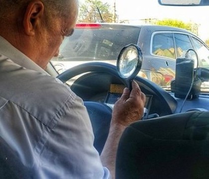 Un taximetrist din capitala isi verifica comenzile pe telefon cu lupa. Imaginea a devenit virala