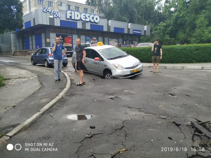 S-a surpat asfaltul! O masina de taxi, blocata dupa ce a intrat cu roata intr-o groapa formata pe o strada din capitala - GALERIE FOTO