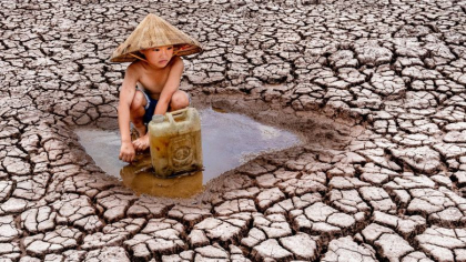 Un copil aduna pentru familia lui ultimele picaturi de apa de pe un camp ars de soare. Imaginile crunte ale secetei din Vietnam