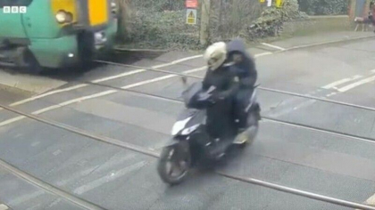 Momentul in care un scuterist trece prin fata unui tren. Barbatul avea in spate un pasager - VIDEO