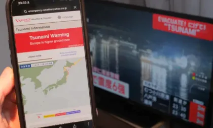 Un monitor TV și un smartphone afișează informații despre cutremurul produs în largul coastei prefecturii Aomori, Japonia, pe 8 decembrie 2025
